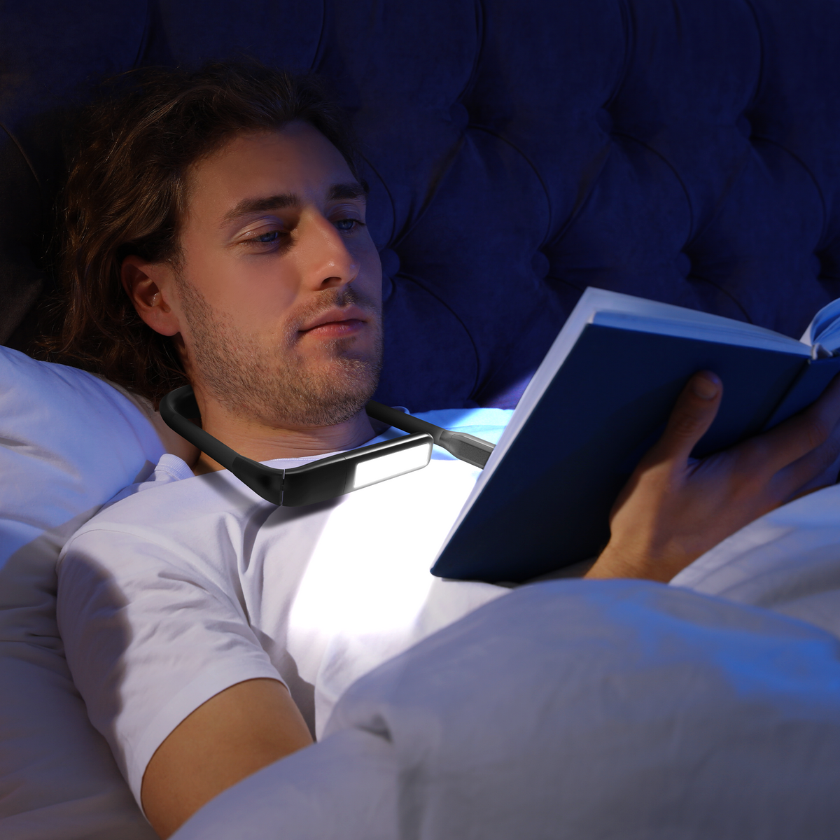 Man reading in bed wearing a neck reading light